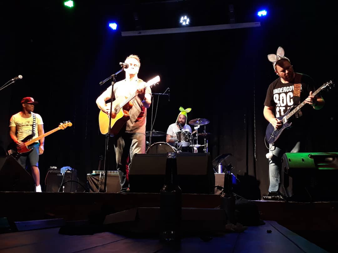 Warren playing guitar on stage with his band in 2018