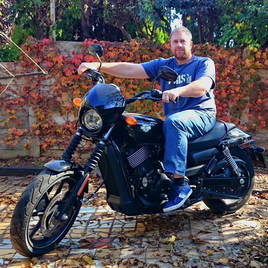 Warren sitting on his Harley-Davidson Street 750 in front of an autumn-leaf backdrop