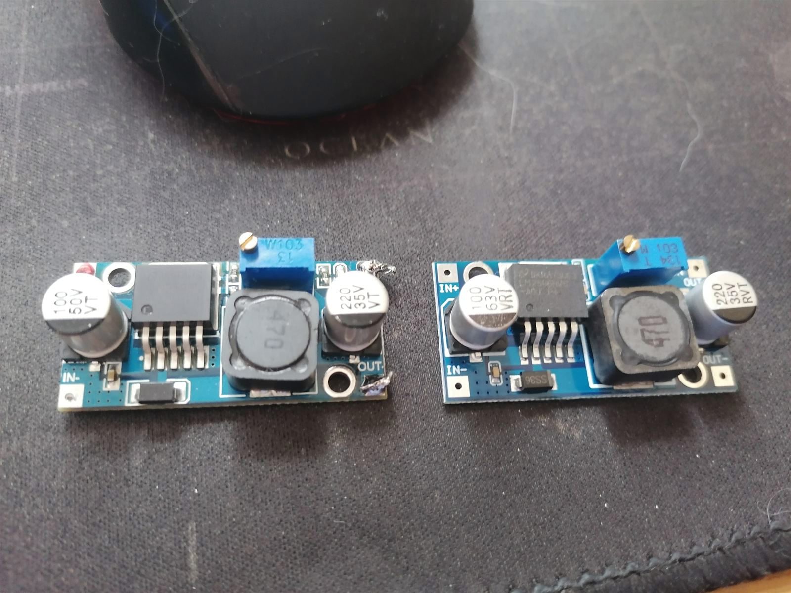 Two buck converter modules side by side, one wearing suspicious solder blobs