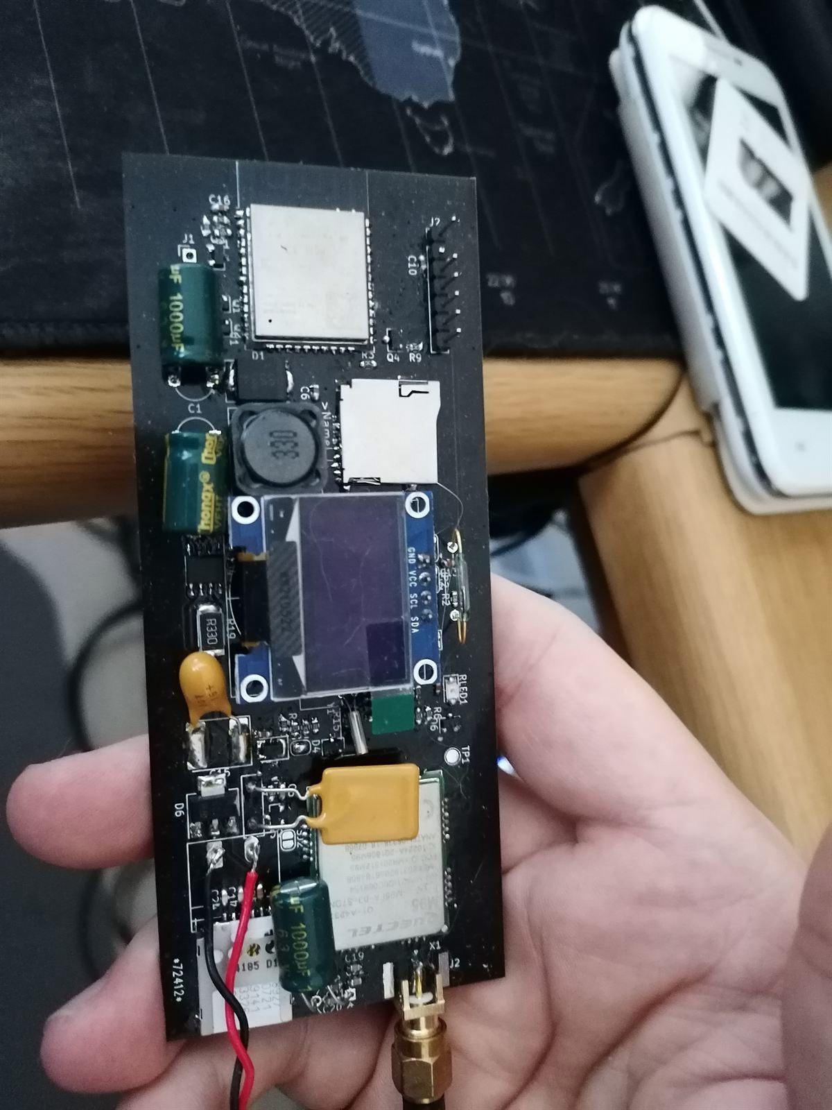 The final version's internals: a custom black PCB with an ESP32 module, SD card slot, OLED screen and cellular modem